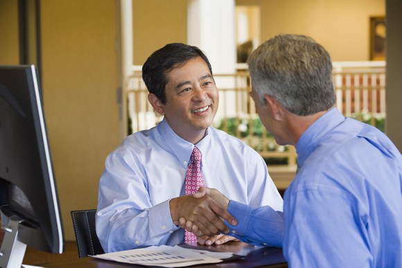 Picture of two people in at desk shaking hands.