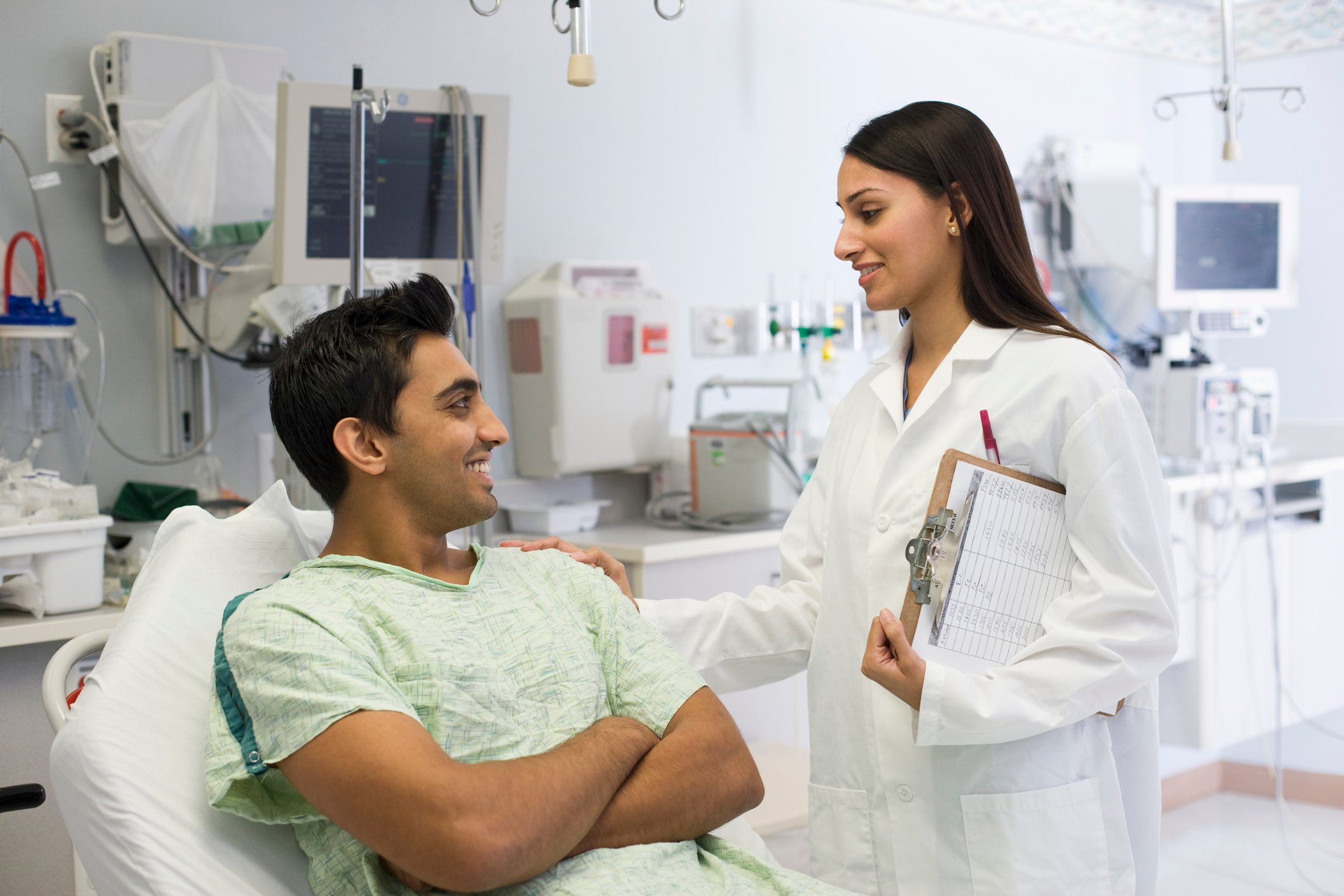 A nurse talking to a patient lying in a hospital bed.