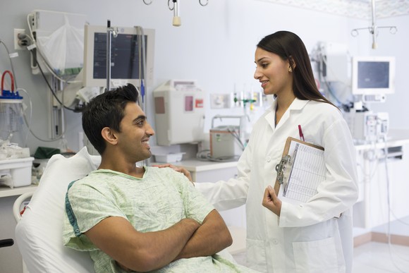 A nurse talking to a patient lying in a hospital bed.