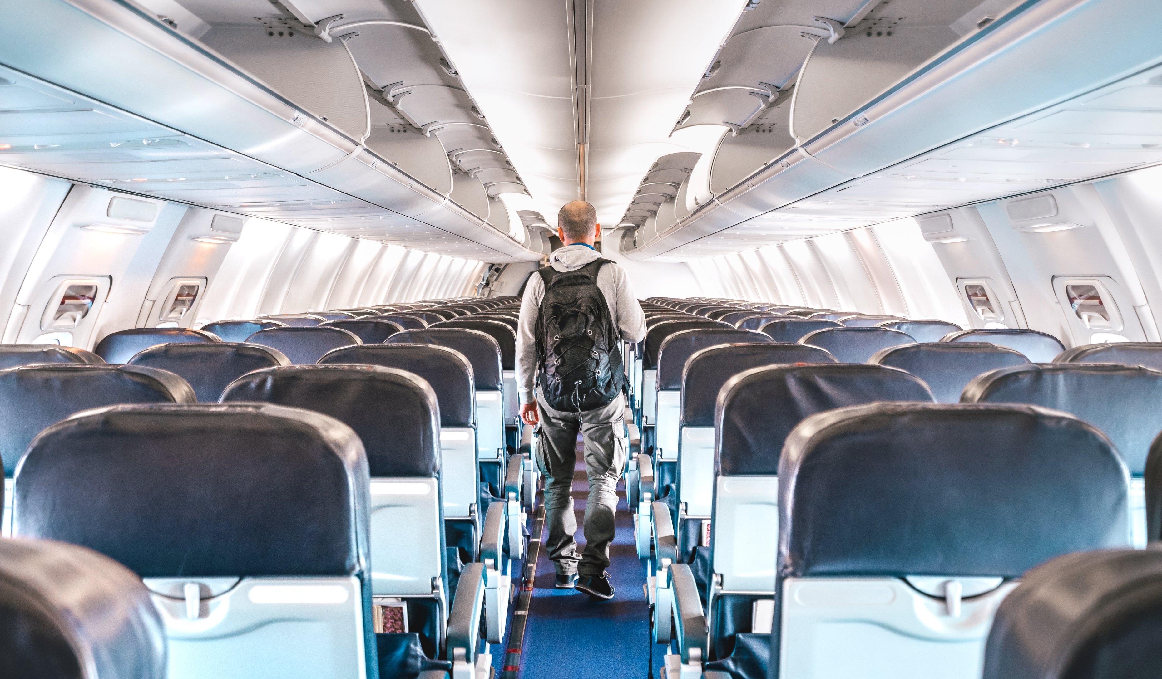 Man walking through an airplane interior.