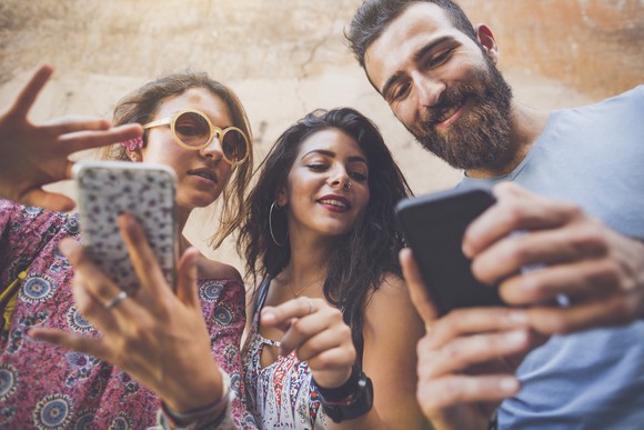 Three people play mobile games.