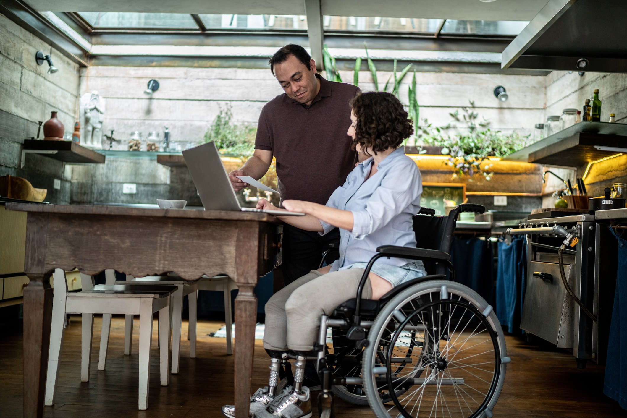 Two people in a kitchen, looking over paper documents and computer files.