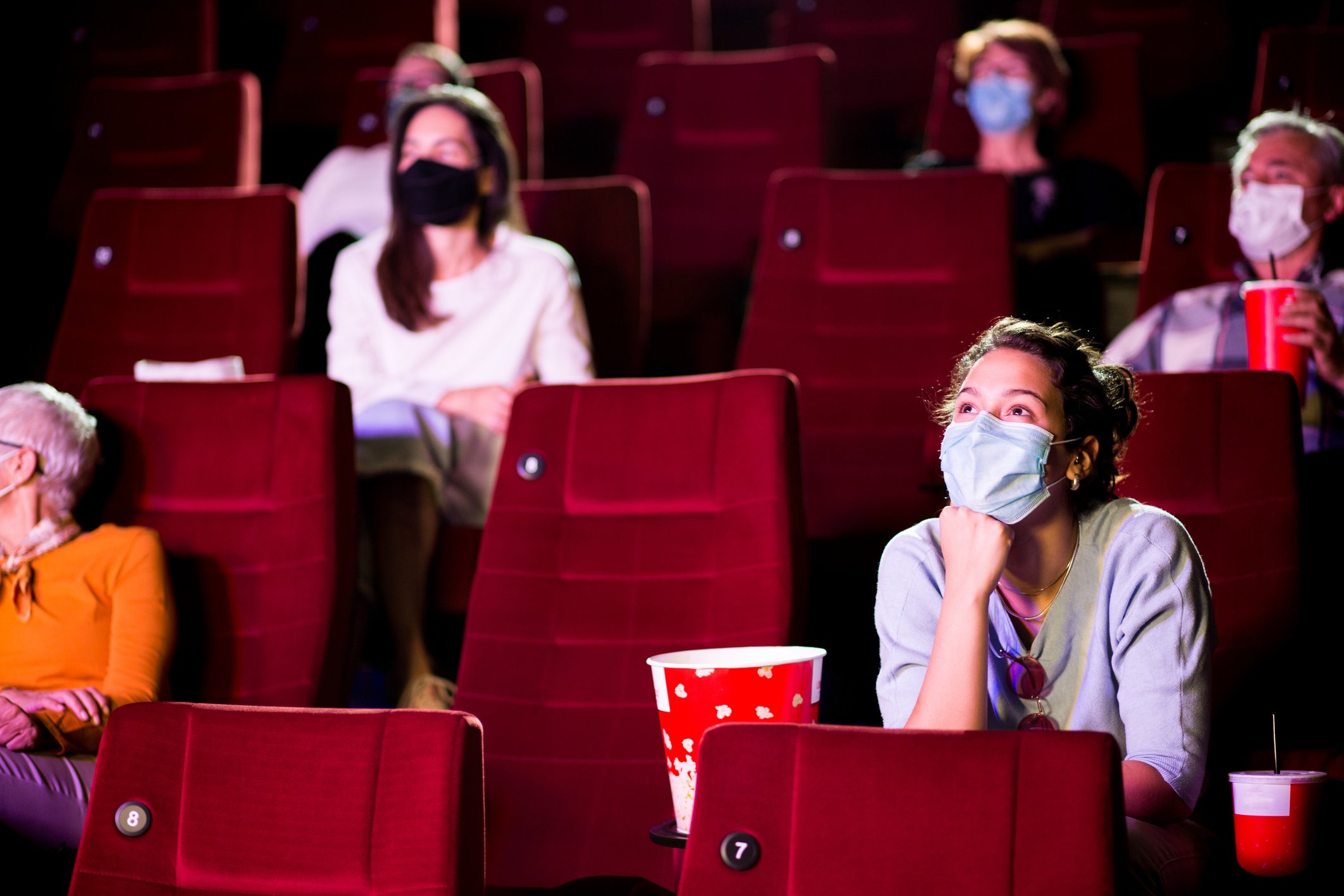 People wearing masks watching a movie in a theater
