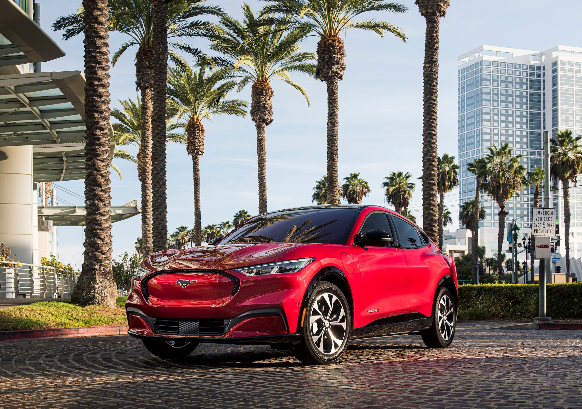 A red 2021 Ford Mustang Mach-E, a sporty electric crossover, parked in front of a Florida hotel. 