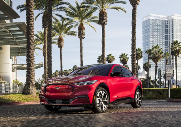 A red 2021 Ford Mustang Mach-E, a sporty electric crossover, parked in front of a Florida hotel. 