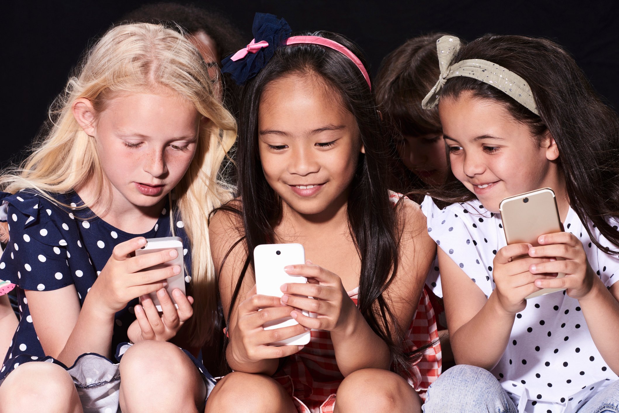 Three children each holding a phone while sharing what they see on social media.