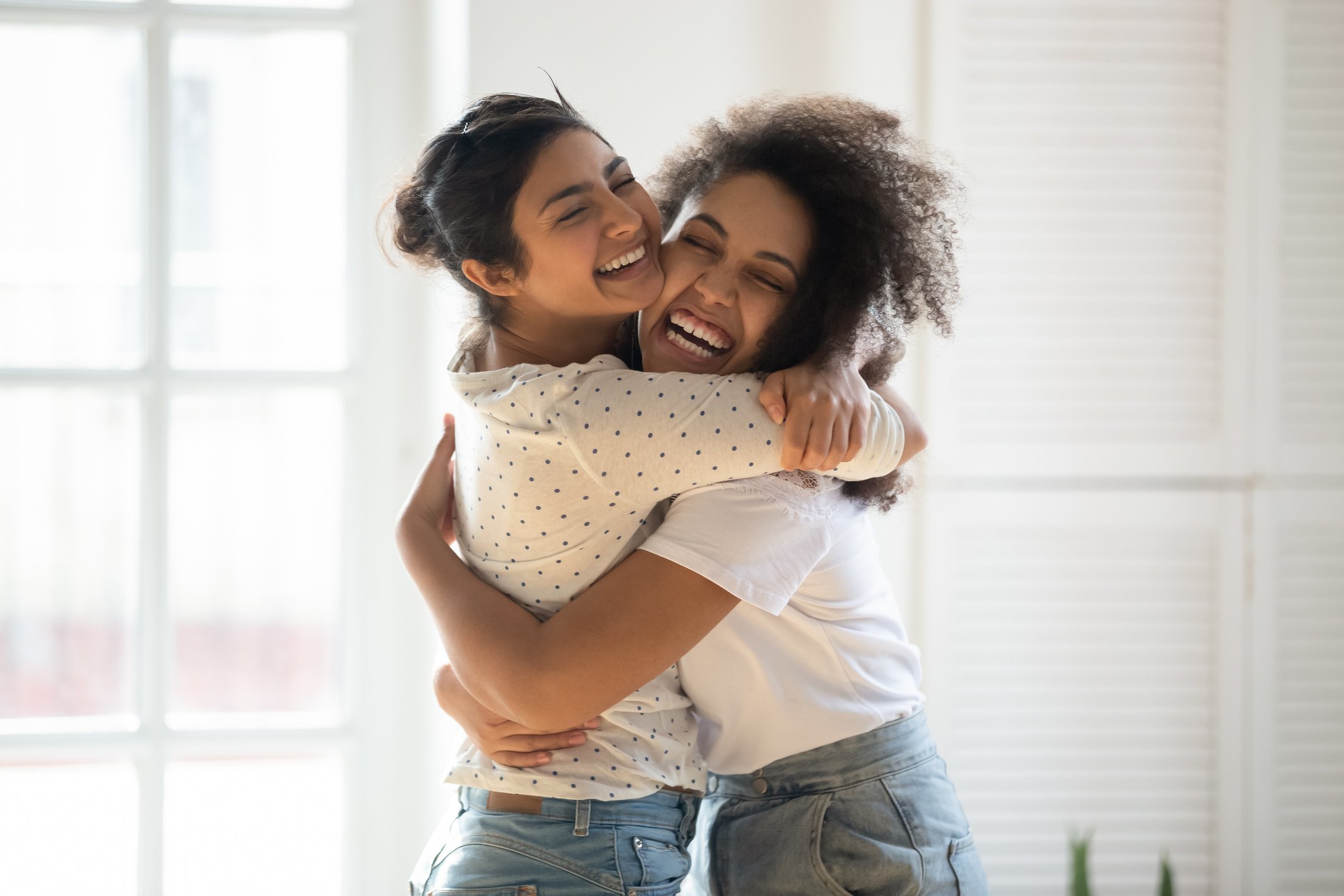 Two young people hugging indoors. 