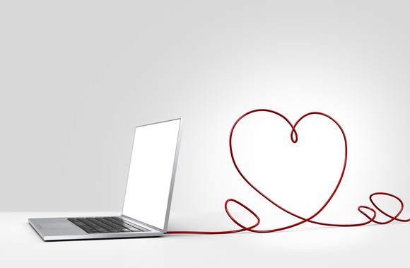 Computer with a string in the shape of a heart attached to it.
