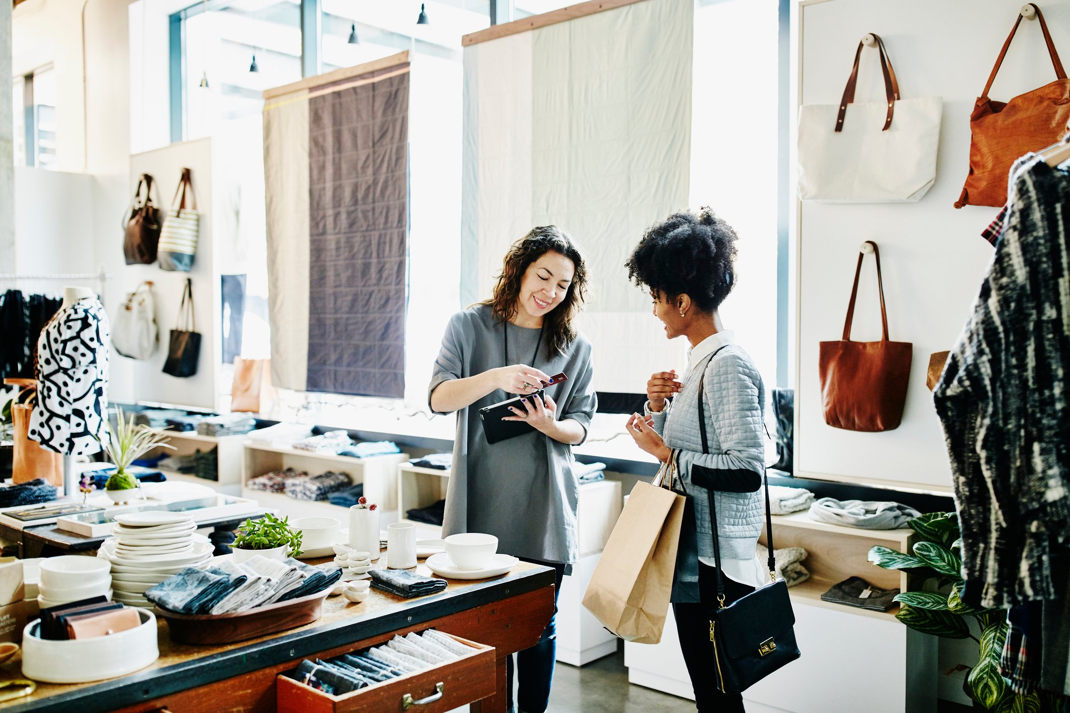 Two smiling shoppers in a clothing store.