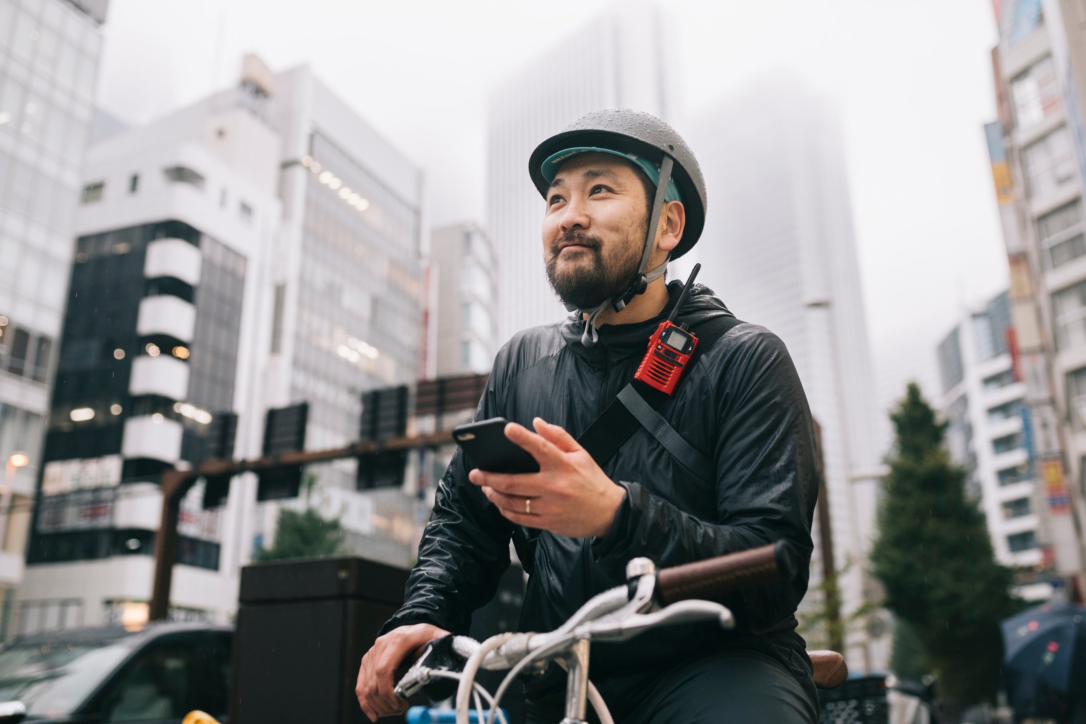 A delivery driver on a bicycle checks for directions on their phone.