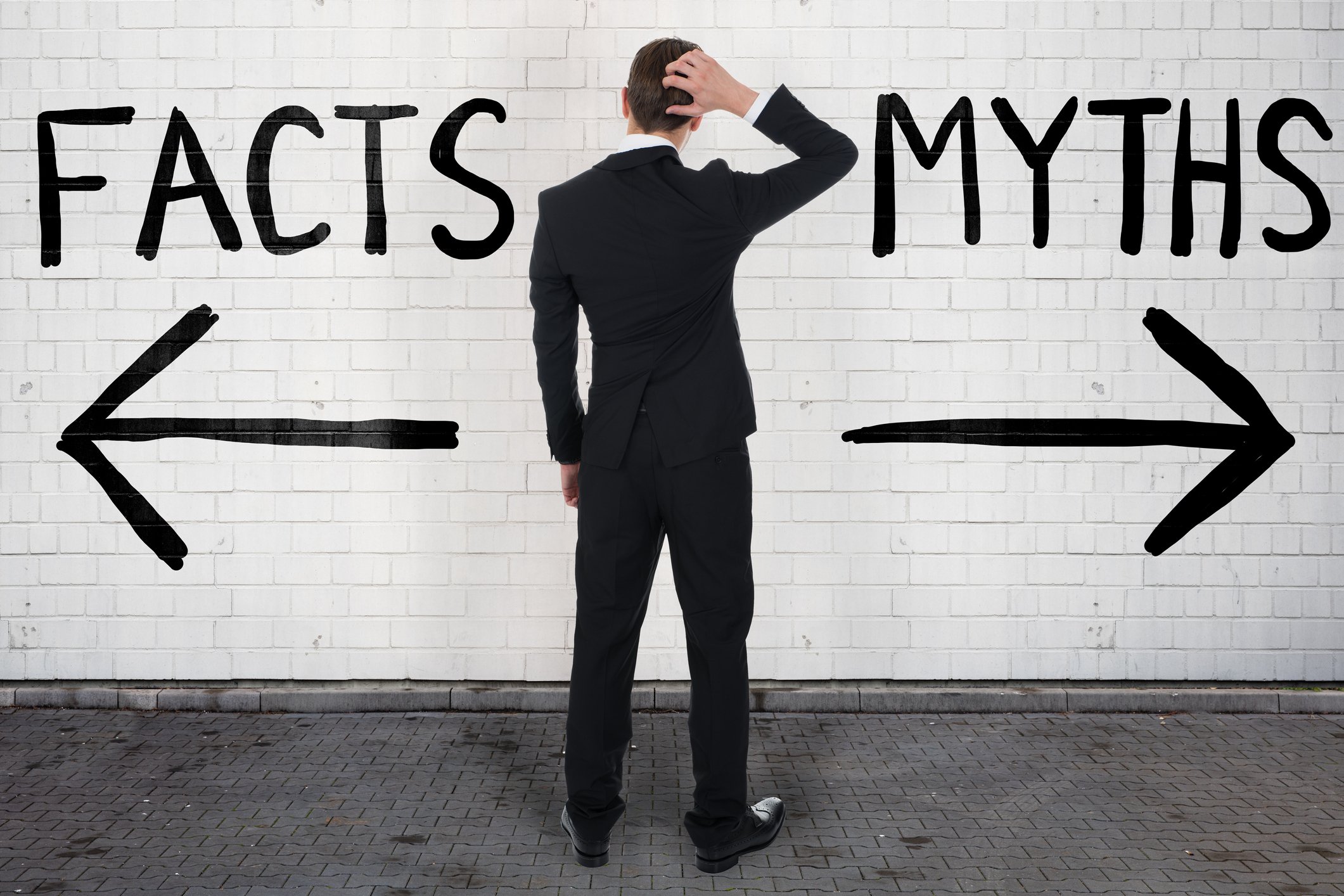 Person looking at opposing signposts reading Facts and Myths.