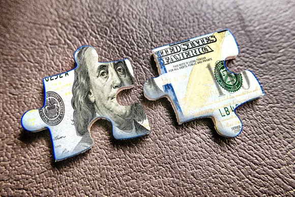 Two jigsaw puzzle pieces that form part of a $100 bill.