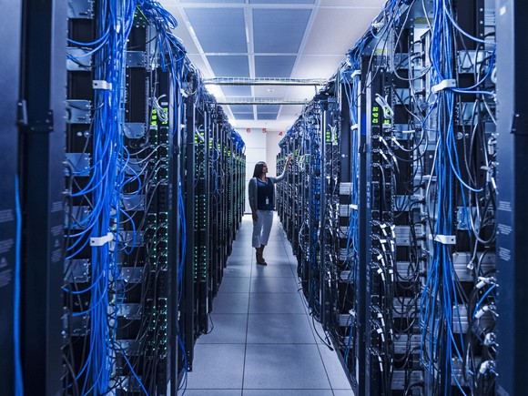 A woman in a room full of computer servers.
