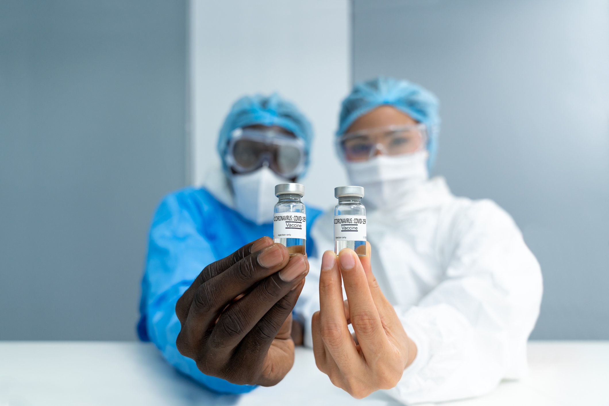 Two researchers hold out vials of coronavirus vaccine.