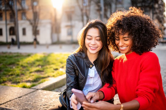 Two people smiling and looking at a smartphone.