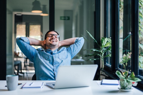 A smiling man sitting at a laptop 