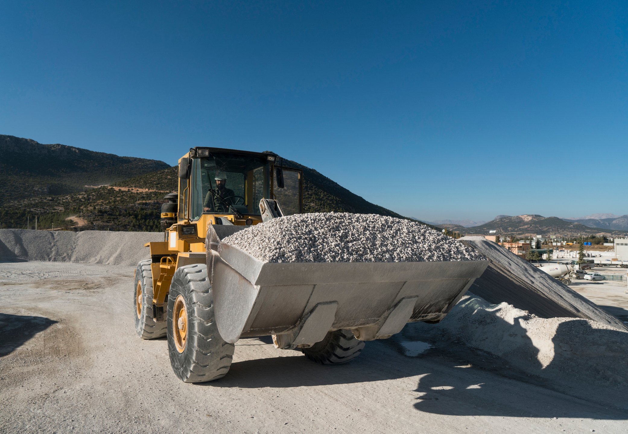 front end loader hauling gravel in rock quarry.