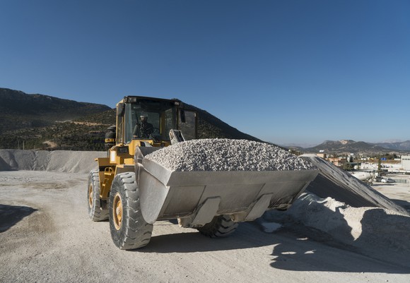 front end loader hauling gravel in rock quarry.