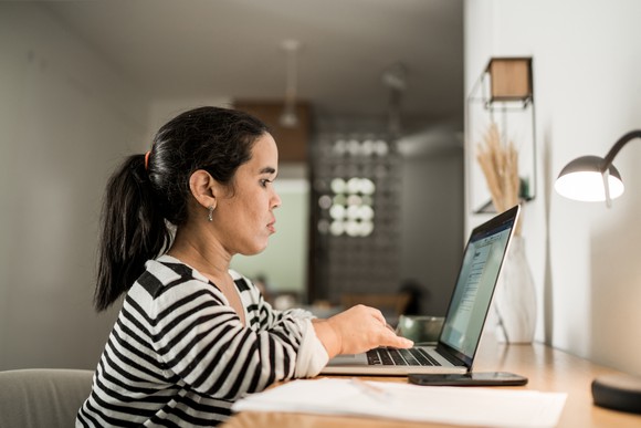 A person sitting at a desk typing on laptop.
