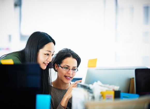 Two business people discussing over a laptop.