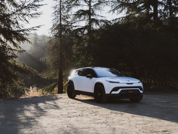 A Fisker Ocean EV parked in a clearing in a forest.