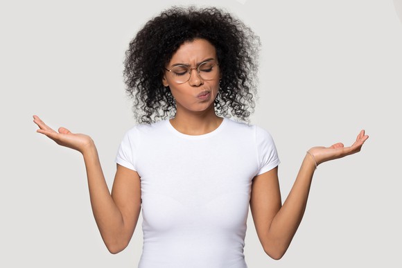 A person with both hands up and a disgruntled expression, trying to weigh two options.