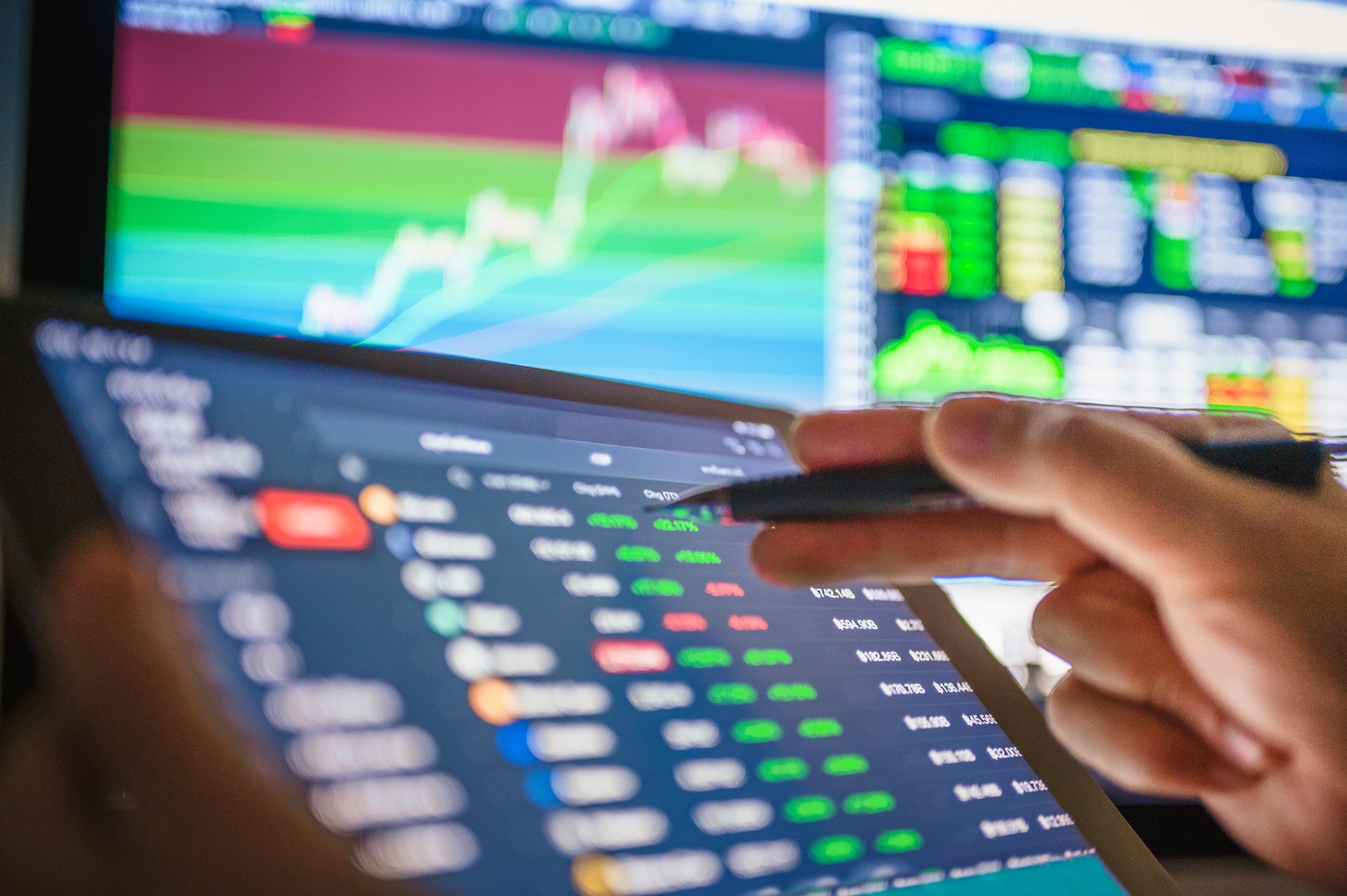 A trader reading a tablet with stock prices on it.