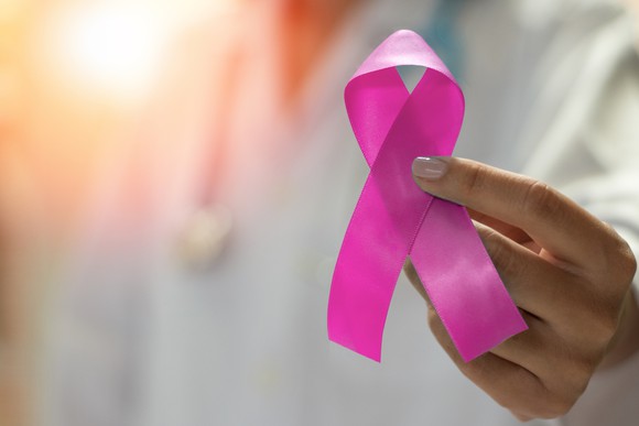 Healthcare professional holding a pink ribbon for breast cancer awareness.