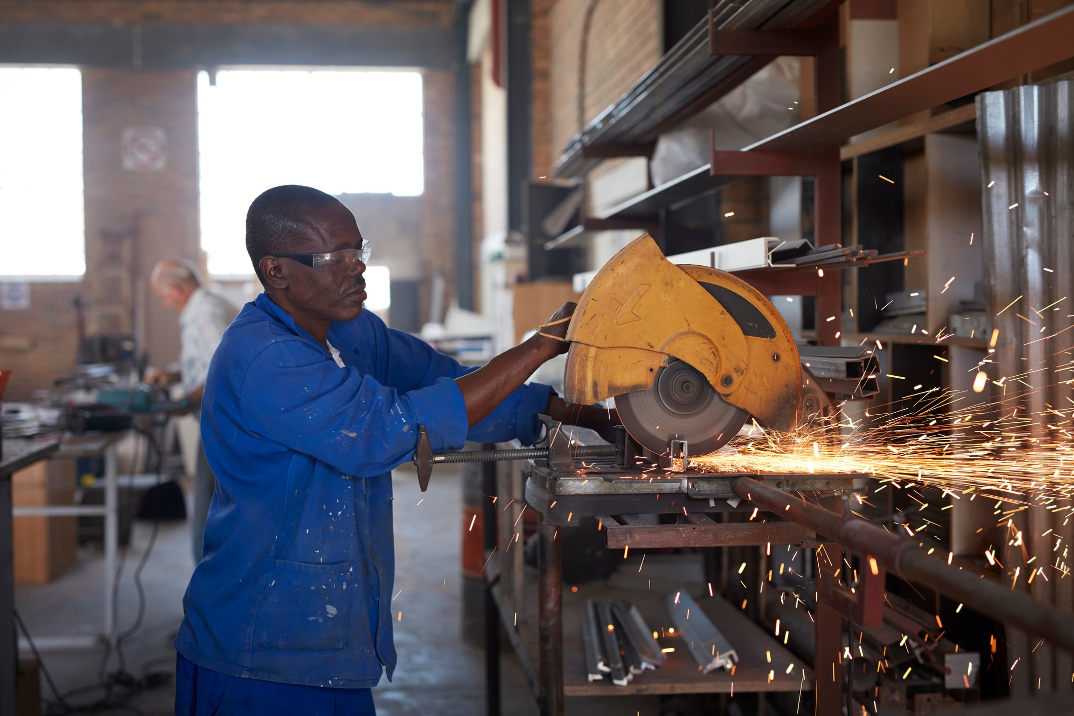 A person cutting steel pipes in a factory.
