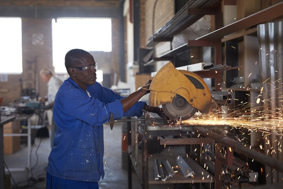 A person cutting steel pipes in a factory.