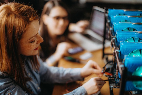 Two people working on a cryptocurrency mining rig.