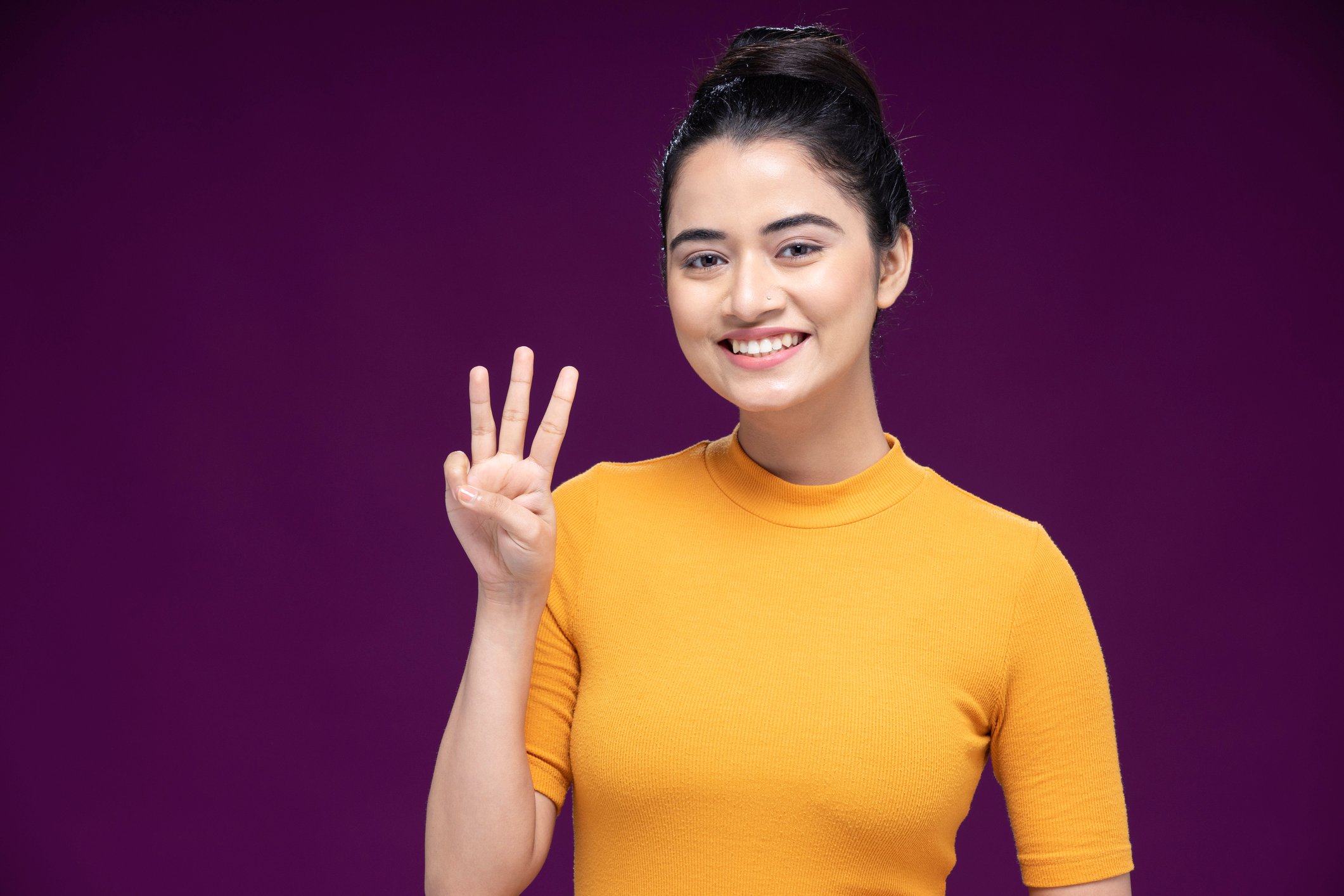 A woman is holding up three fingers.