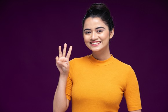 A woman is holding up three fingers.