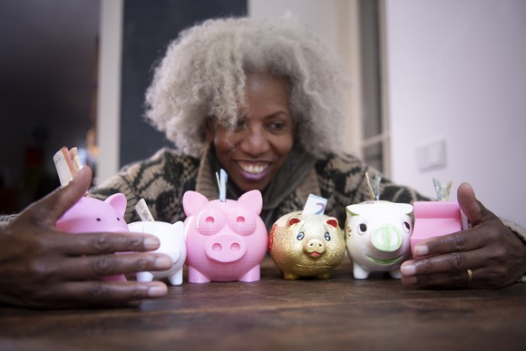 Person with armful of piggy banks.