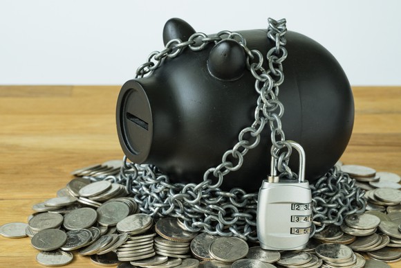 Piggy bank wrapped in chains and surrounded by coins.