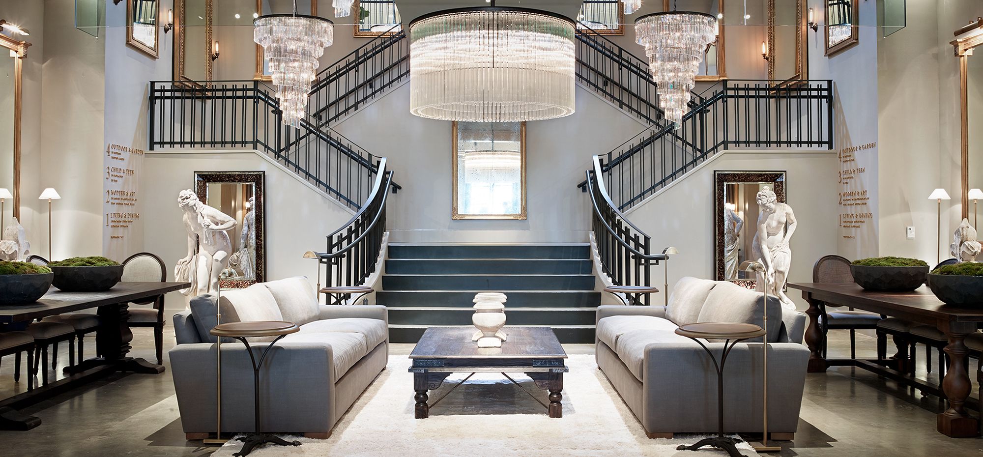 An upscale RH gallery store, with a grand staircase and sitting room furniture.