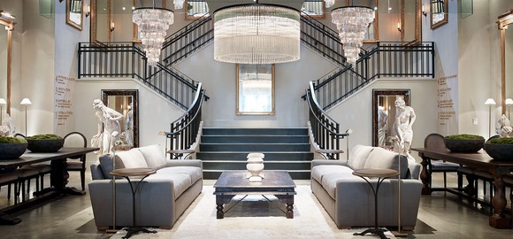 An upscale RH gallery store, with a grand staircase and sitting room furniture.