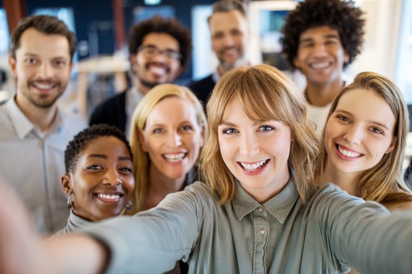 group of smiling people taking selfie.