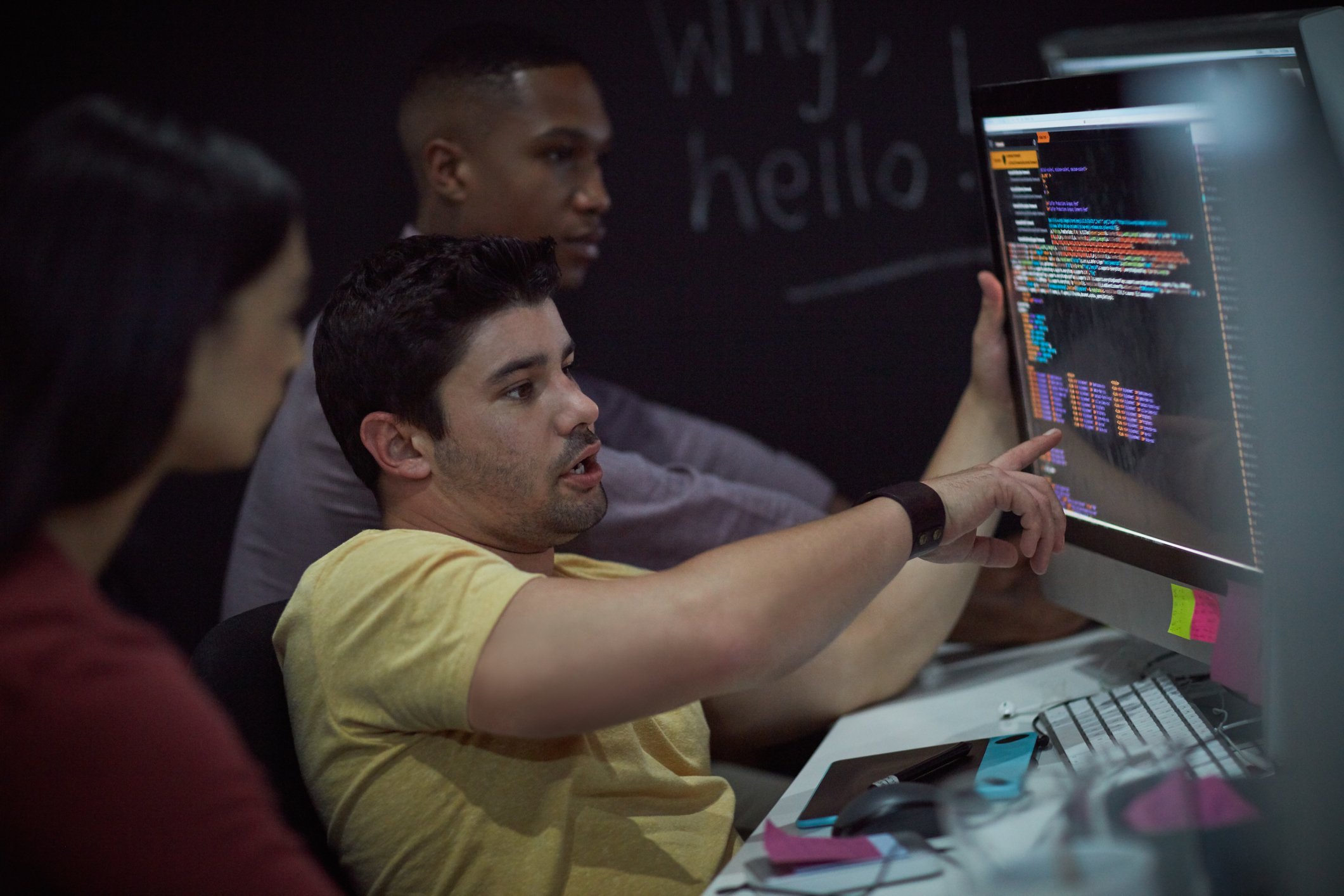 Three IT workers looking at computer screen.