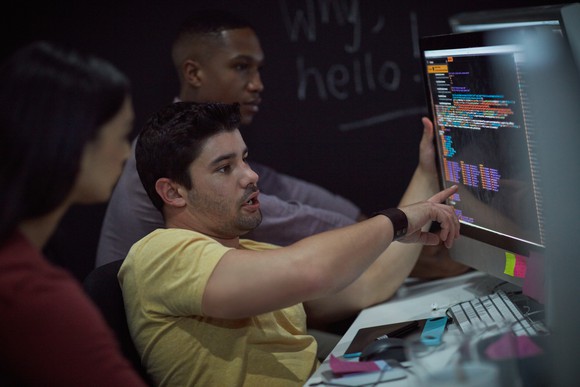 Three IT workers looking at computer screen.