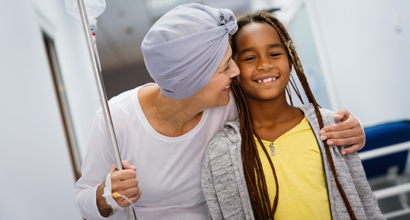 Cancer patient with IV smiling with child.