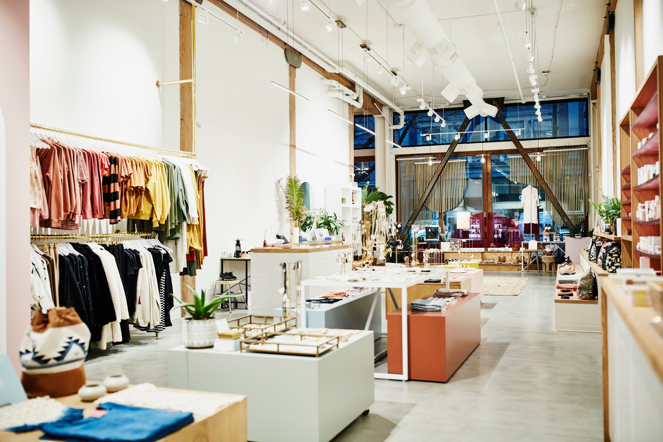 A brightly lit boutique store with a shelf of clothing and other luxury items on display.