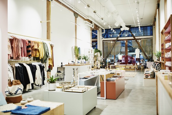 A brightly lit boutique store with a shelf of clothing and other luxury items on display.