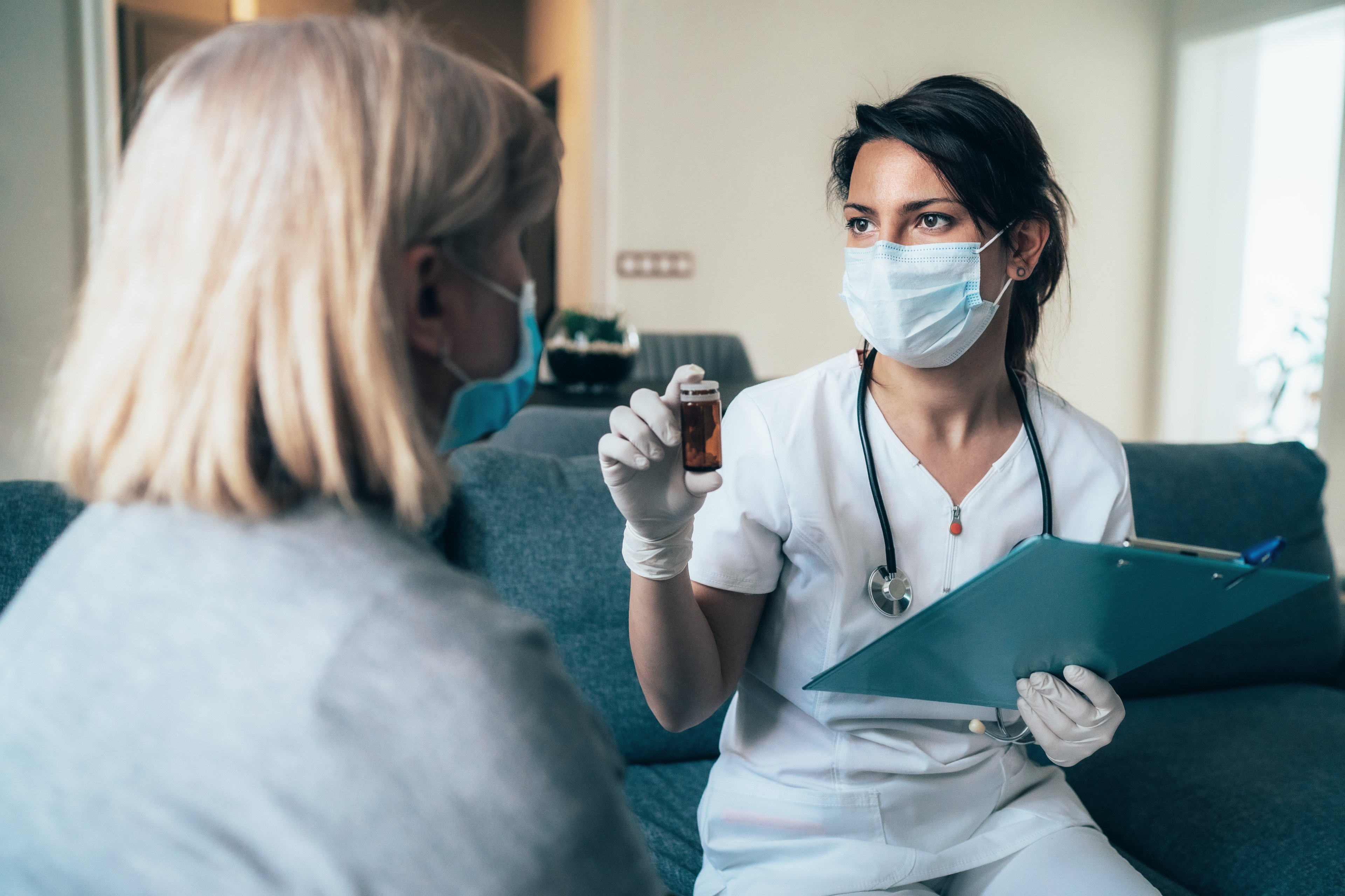 Doctor giving patient an oral coronavirus vaccine pill bottle. 