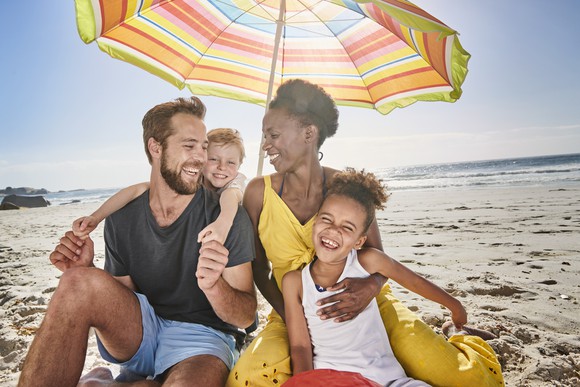 A happy family of four on a beach. 