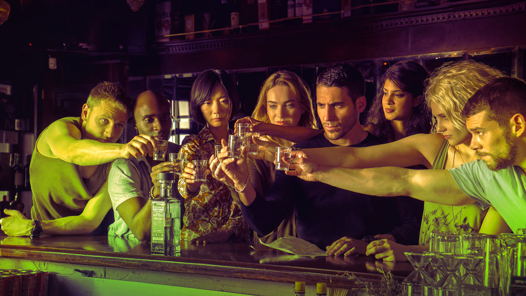 The cast of Netflix's Sense 8 raising a toast in a bar.