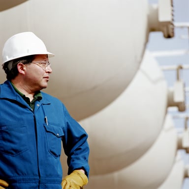 Man wearing hard hat at an oil refinery.