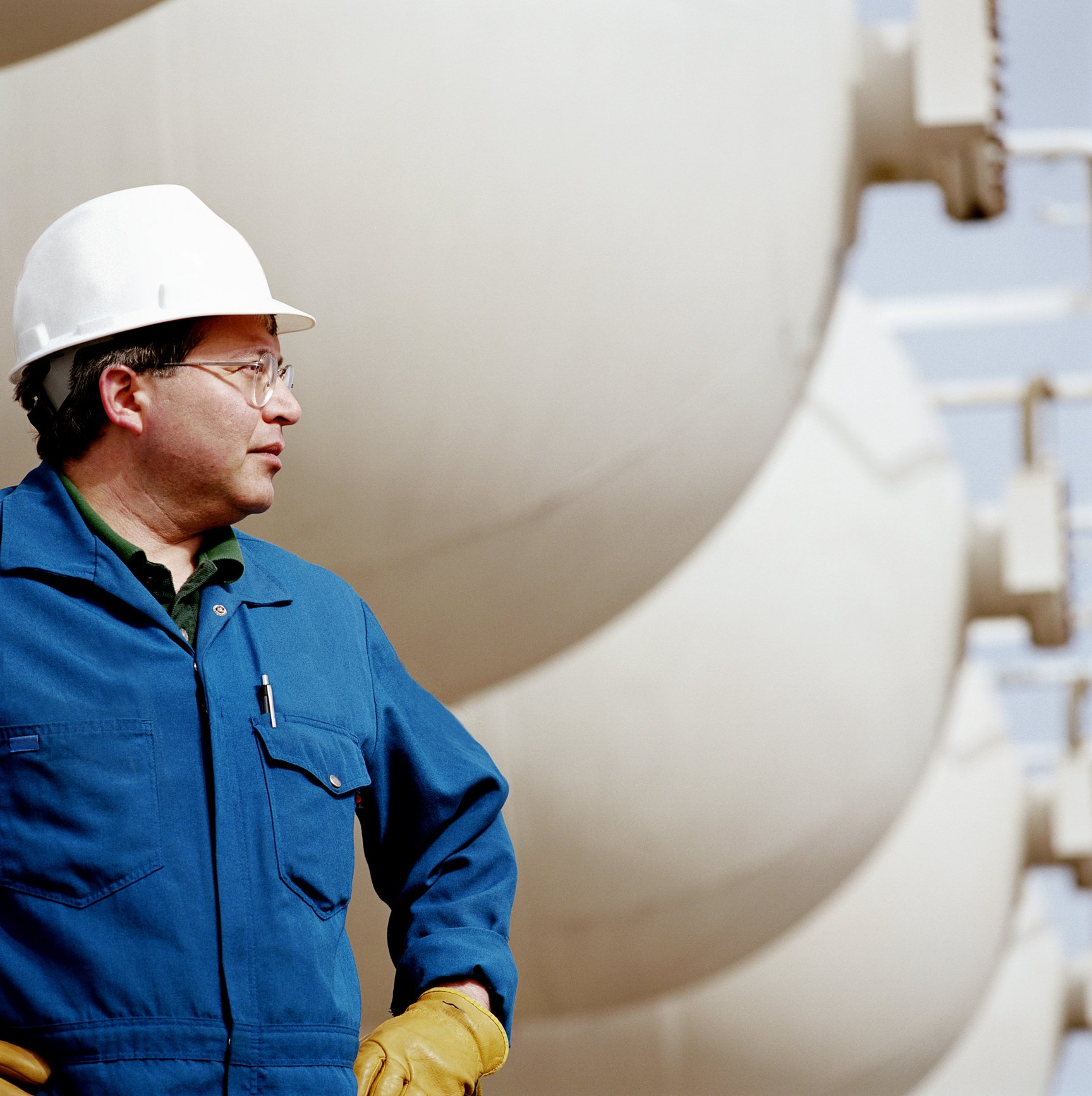 Man wearing hard hat at an oil refinery.