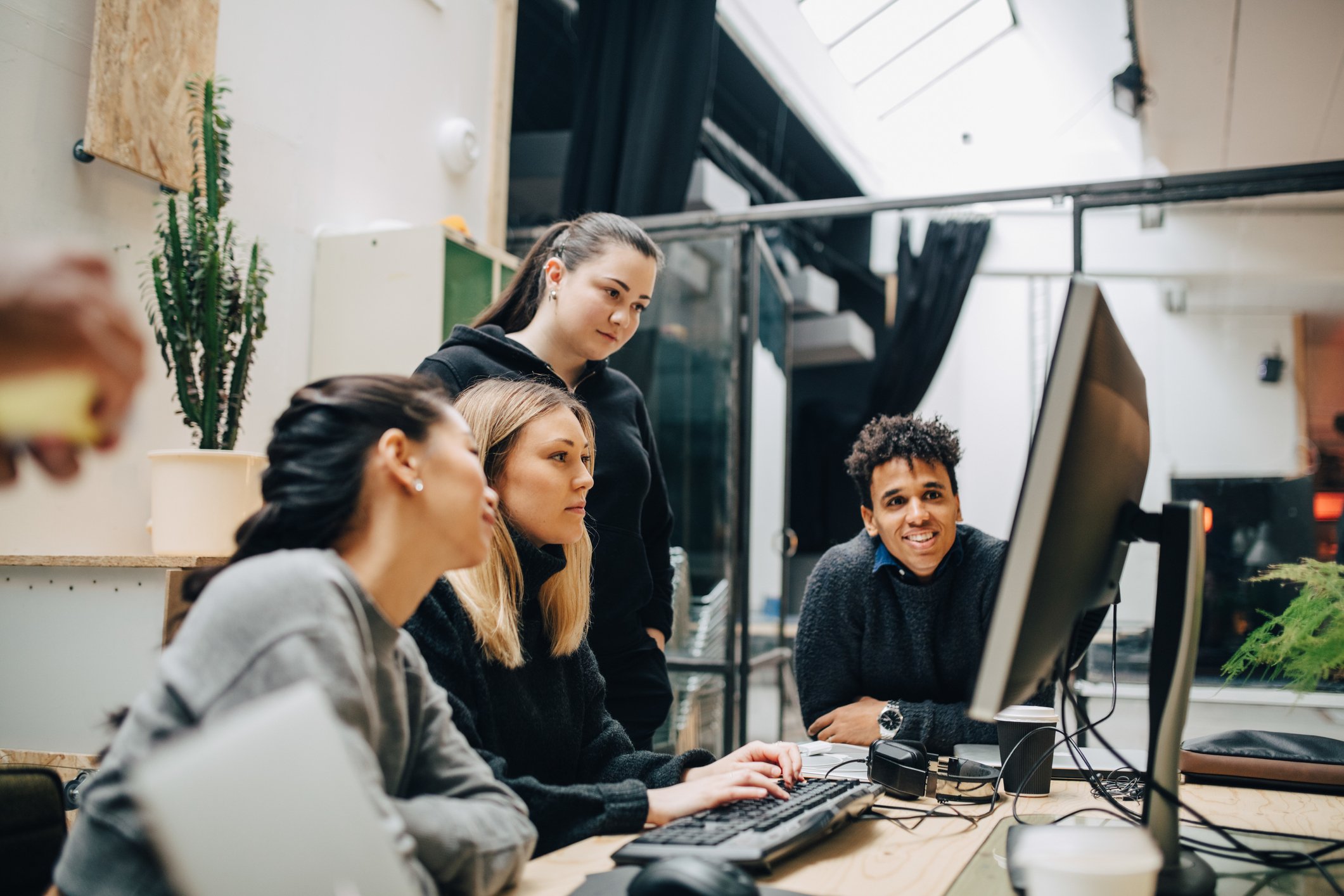 Four people work together in front of a computer.