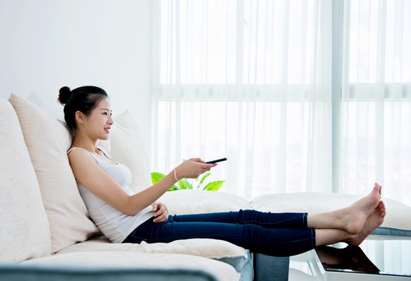 A person holding a remote while sitting down.